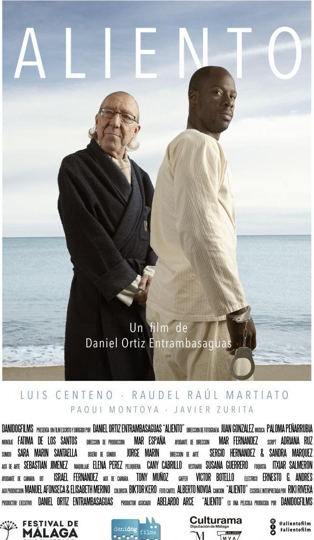 Cartel del largometraje Aliento. Composición fotográfica. aparece un hombre mayor de 70 años y un chico de color que representa a un inmigrante. ambos visten en pijama. Se ve de fondo una imagen de la playa.